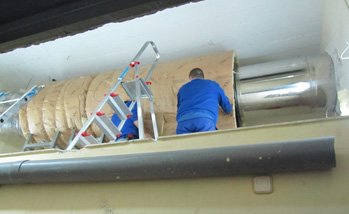 A duct silencer being installed to attenuate low frequency noise through the chimney of the heating system